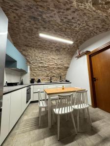 a kitchen with a table and chairs and a stone wall at Casa Di Lithos in Mestá