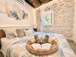 a bed with a basket of towels and shoes on it at Stonehouse Kotor Bay in Kotor