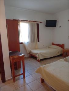 a room with two beds and a tv and a window at Benigna Studios in Leipsoi