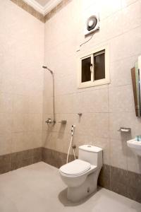 a bathroom with a toilet and a shower and a window at شقق شاطئ الواحة in Jeddah