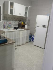 a kitchen with a white refrigerator and white cabinets at Darna in Raʼs al Jabal