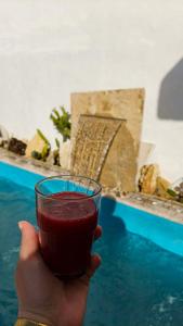 a hand holding a glass of red liquid next to a pool at Darna in Raʼs al Jabal