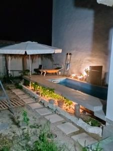 a patio with an umbrella and a pool at night at Darna in Raʼs al Jabal