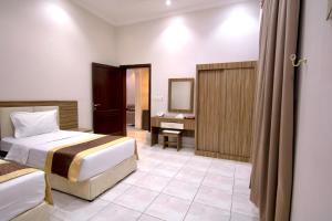 a hotel room with two beds and a desk at شقق شاطئ الواحة in Jeddah +5 photos
