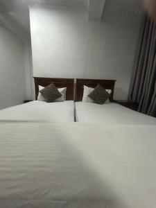 two beds in a bedroom with white sheets and pillows at Urban Vibe Kandy in Kandy