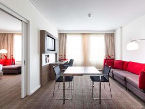 a living room with a couch and a table and chairs at Novotel Melbourne Glen Waverley in Glen Waverley