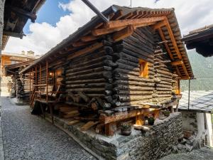 a wooden house with a pile of logs at Alpine Majestic Rascard - Unique Mountain Experience with Balcony and panoramic views in Champoluc
