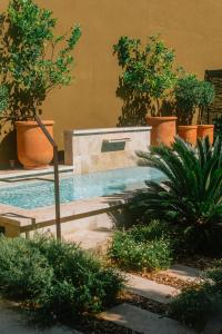 a swimming pool in a garden with trees and plants at MARCELLE EN CAMARGUE - intra muros - piscine et jardin - petit déjeuner compris in Aigues-Mortes