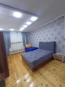 a bedroom with a blue bed and a wooden floor at Qebele gunluk ev in Bum +8 photos