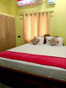 a bedroom with a large bed with a red blanket at BHS Deluxe Rooms in Puri