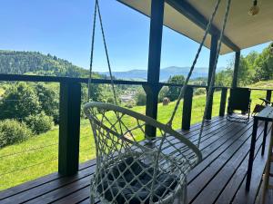 a swinging chair on a porch with mountains in the background at Borzhava View Chalet in Nizhniy Studenyy