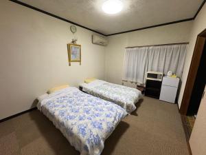 a bedroom with two beds and a desk and a window at 民泊SakuraワンちゃんＯＫ in Karatsu
