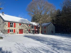 a stone barn with red doors in the snow at Ferme de Chaudeyrac in Saint-Front