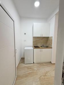 a small kitchen with white cabinets and a sink at Duraku Apartments in Ulcinj +16 photos