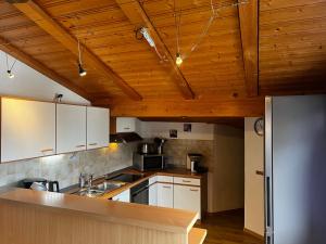 a kitchen with white cabinets and a wooden ceiling at Landhaus Alpenstern in Riezlern