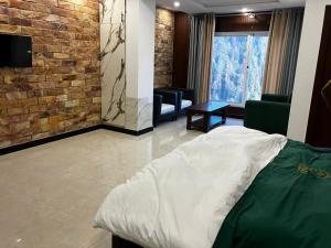 a bedroom with a bed and a brick wall at Landmark Hotel & Resort in Taiwāl