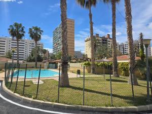 a fence in front of a swimming pool with palm trees at Villa Flores in Alicante