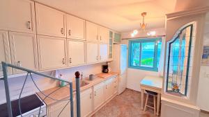 a kitchen with white cabinets and a window at Aurora Maris Maisonette in Possidi