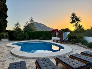 a pool in a yard with chairs and a sunset at Secrets Rural House in Jávea