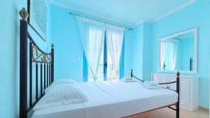 a bedroom with a bed with a blue wall at Aurora Maris Maisonette in Possidi