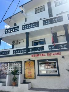 a white building with a sign that reads international restaurant at Hotel HILLMON in Sosúa