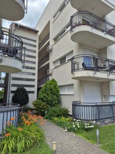 an apartment building with balconies and flowers in a yard at Noémi Wellness Apartman in Siófok