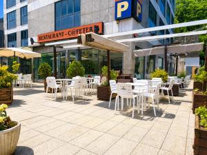 eine Terrasse mit weißen Stühlen und Tischen vor einem Gebäude in der Unterkunft Zenit Diplomatic in Andorra la Vella