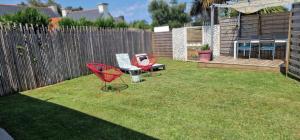 two red chairs and a table in a yard at Étoiles et Désirs in Kermaria-Sulard