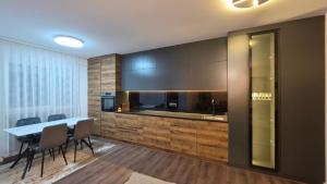 a dining room with a table and chairs and a kitchen at Pines Apartment in Kosovo Polje