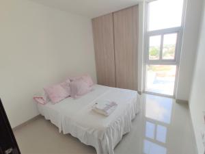 a bedroom with a bed with pink pillows and a window at Atlantis Tower in Santa Cruz de la Sierra +7 photos