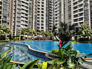 a large swimming pool with palm trees and large buildings at Amberside Coastal Breeze Oasis in Johor Bahru