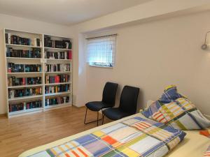 a bedroom with a bed and two chairs and bookshelves at FeWo Ruhe in Hohenems