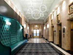 a hallway with a green couch and a chandelier at Sofitel Lafayette Square Washington DC in Washington, D.C.