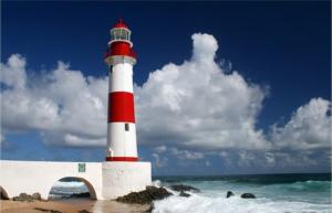 a red and white lighthouse sitting on the beach at Hostel salvador itapua in Salvador