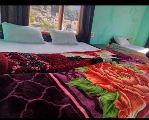 a bed with a colorful comforter and a window at Hariyali Homestay in Sari