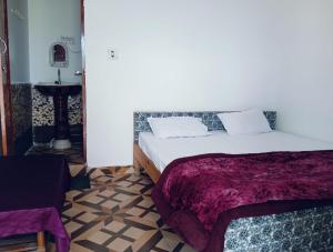 a bedroom with a large bed with a purple blanket at Hariyali Homestay in Sari