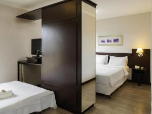 a hotel room with two beds and a large closet at Mercure Jaragua do Sul in Jaraguá do Sul