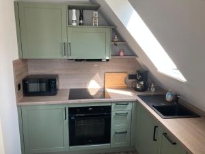 a kitchen with green cabinets and a sink and a microwave at Ferienwohnung am Woezer See in Woez
