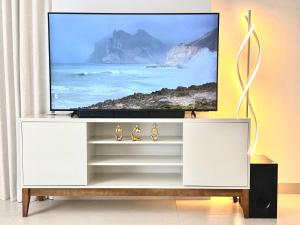 a white entertainment center with a flat screen tv on it at Ajmal Makan City in Sharjah