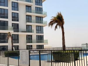a building with a palm tree and a swimming pool at Ajmal Makan City in Sharjah