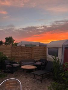 a patio with a table and chairs and a trailer at Przyczepa Kempingowa Beige in Jastarnia