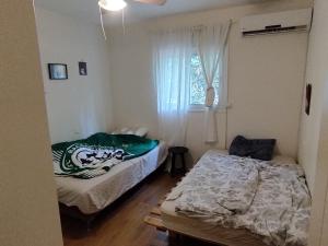 a bedroom with two beds and a window at SnirBen zvi in Kibbutz Snir