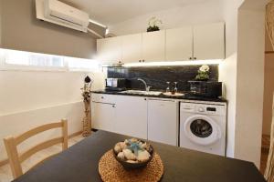 a kitchen with a washing machine and a table with a bowl at Rhodes Beach Side Houses in Ixia
