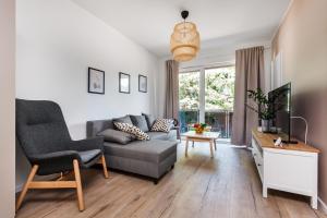 a living room with a couch and a chair at Apartamenty Pilice - basen, sauny, atrakcje dla dzieci w cenie - 250m in Jastrzębia Góra