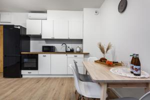 a kitchen with white cabinets and a wooden table at Apartamenty Pilice - basen, sauny, atrakcje dla dzieci w cenie - 250m in Jastrzębia Góra