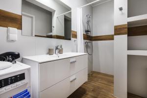 a white bathroom with a sink and a shower at Apartamenty Pilice - basen, sauny, atrakcje dla dzieci w cenie - 250m in Jastrzębia Góra