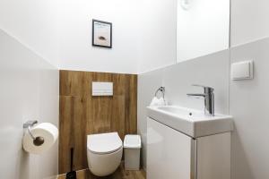 a white bathroom with a toilet and a sink at Apartamenty Pilice - basen, sauny, atrakcje dla dzieci w cenie - 250m in Jastrzębia Góra +45 photos