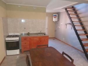a kitchen with a sink and a stove and a staircase at Lo de Rolo in Huerta Grande