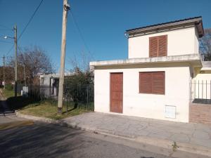 a white house with a brown door on a street at Lo de Rolo in Huerta Grande