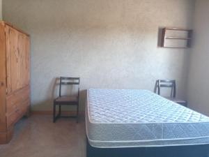 a bedroom with a bed and two chairs at Lo de Rolo in Huerta Grande